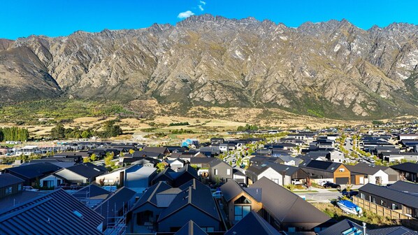 A residential area with modern houses, a clear view of mountains, and a small body of water. - Executive 3BR 3Queen-Beds Free Unltd WiFi & Garage (Queenstown)
