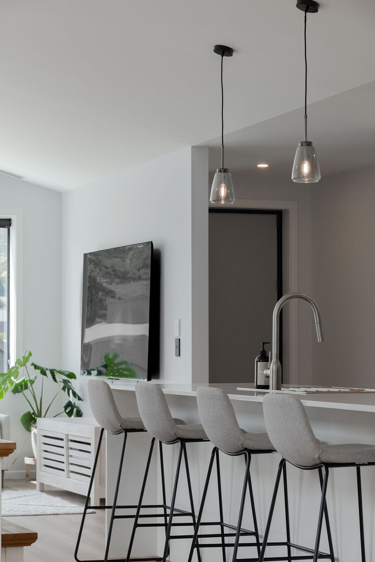 A modern kitchen with a bar area, pendant lights, and a large window.