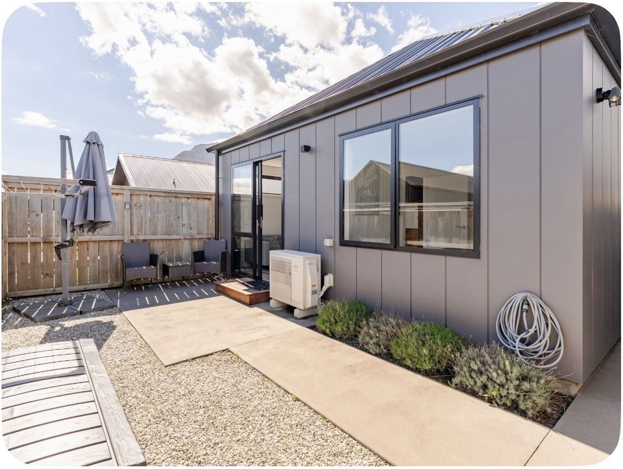 Une maison moderne dotée d’un patio, de mobilier d’extérieur et d’un appareil de climatisation.
