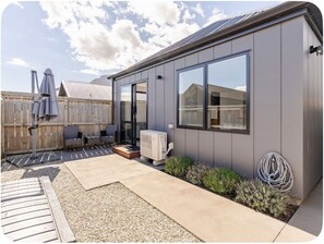 A modern house with a patio, outdoor furniture, and an air conditioning unit. - Remarkable’s Escape 5Mins Ski Field 7Mins Airport (Queenstown)