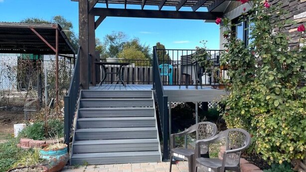 A covered outdoor area with a pergola, steps leading to a balcony, and a patio with chairs. - Comfortable, Spacious home with pool table•firepit• great location (South Jordan)