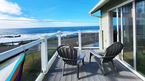 Une terrasse en bois avec deux chaises et une table, d’où l’on a une vue sur l’océan.