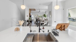A modern kitchen with a central island, stainless steel sink, and pendant lighting. - Luxury home Minutes to Armature works & Downtown! (Tampa)