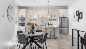 A modern kitchen with light wood cabinets, stainless steel appliances, and a central island with seating. - Luxury home Minutes to Armature works & Downtown! (Tampa)