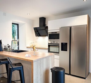 Una cocina moderna con una isla central, electrodomésticos de acero inoxidable y un cubo de basura negro.