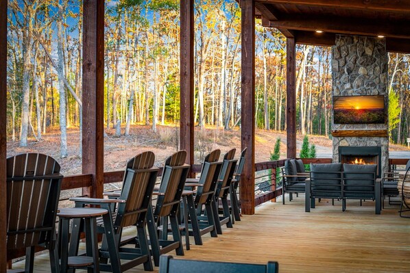 Une terrasse en bois avec des fauteuils Adirondack et une cheminée en pierre.
