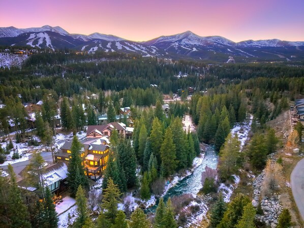 A lodge with a large central building surrounded by dense forest and a river.