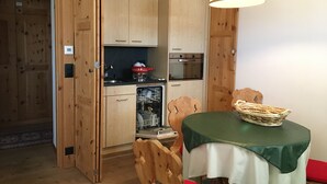 Une cuisine compacte dotée de meubles en bois, d’un lave-vaisselle et d’un coin repas avec une table et des chaises.