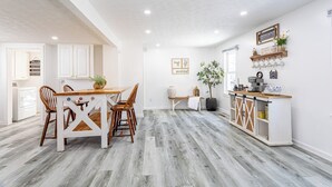 A spacious kitchen with a wooden dining table, white cabinets, and a built-in island with a coffee machine. - House in North Rose, NY, 10 minutes from the beach (North rose)