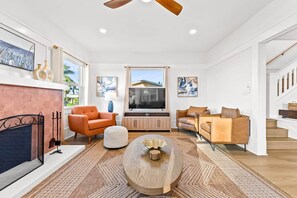 A spacious living room with a fireplace, seating area, and a television.