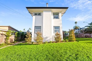 A two-story building with a flat roof, a chimney, and a well-maintained lawn in front.