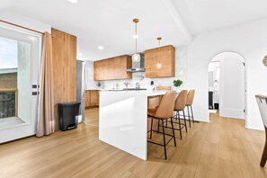 A modern kitchen with wooden cabinets, a white island, and bar stools.