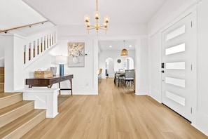 A modern interior with a staircase, a dining area, and a hallway leading to a door.
