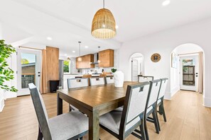 A modern kitchen with wooden cabinets, a central island, and pendant lighting.