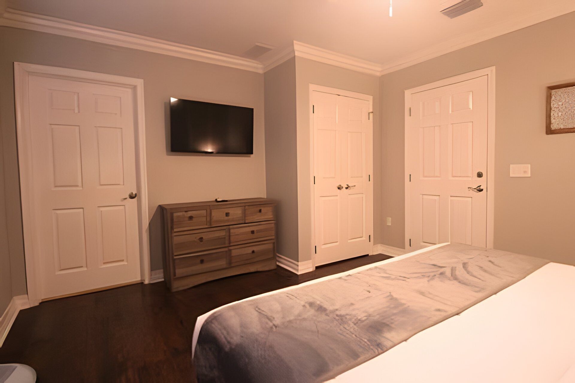 A bedroom with a bed, dresser, and a TV mounted on the wall.