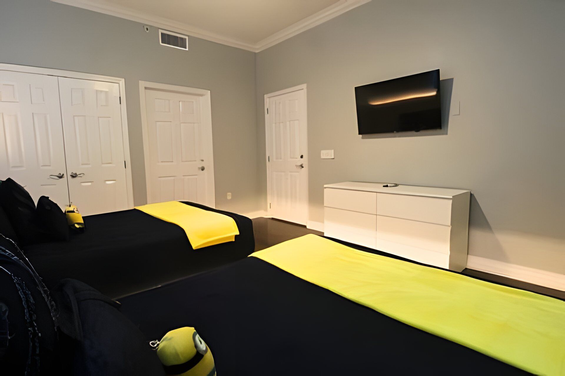 A hotel room with two beds, a TV on the wall, and a white dresser.