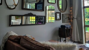 A room with multiple mirrors on the wall, a brown leather sofa, and a small table with a lamp.