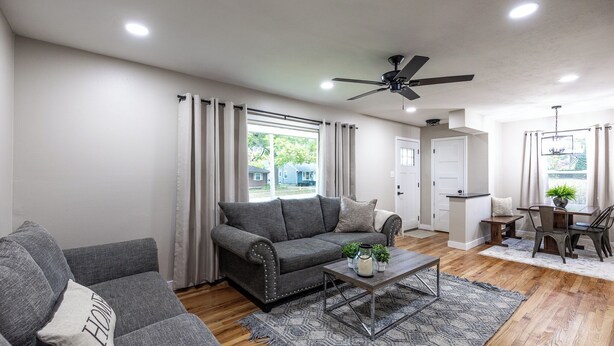 A modern living room with a grey sofa, a coffee table, and a dining area with a table and chairs.
