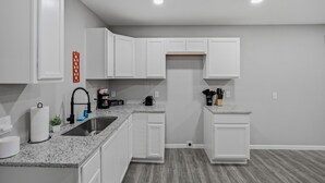 A modern kitchen with white cabinets, granite countertops, and a built-in oven. - Spacious 3BR Retreat Near Downtown River Walk (San Antonio)