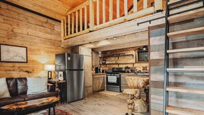 Una cucina accogliente in stile chalet, con finiture in legno, un'area pranzo con una panca e una camera soppalcata con ringhiera in legno.