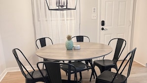 A dining area with a round table, six chairs, a pineapple centerpiece, and a hanging light fixture. - Welcoming 3-bedroom house near Charlotte Airport and Uptown (Charlotte)
