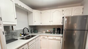 A kitchen with white cabinets, a stainless steel refrigerator, a sink, and a coffee maker. - Welcoming 3-bedroom house near Charlotte Airport and Uptown (Charlotte)