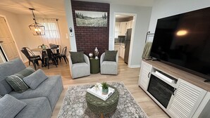 A modern living room with a grey sofa, a coffee table with a plant, a flat-screen TV, and a fireplace. - Welcoming 3-bedroom house near Charlotte Airport and Uptown (Charlotte)
