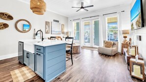 A spacious kitchen with a blue island, wooden flooring, and a ceiling fan. - Gulf Place 210- Steps To Beach *Snowbirds Welcome* Large Balcony (Santa Rosa Beach)