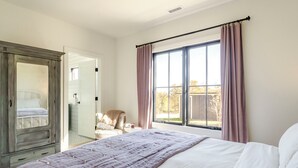 A bedroom with a large bed, a wardrobe, a chair, and a window with curtains. - Fox Cottage – Modern Wine Country Retreat in Afton, VA (Afton)