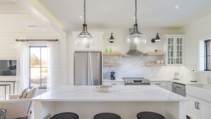 A modern kitchen with a large island, stainless steel appliances, pendant lighting, and a view of the outdoors. - Fox Cottage – Modern Wine Country Retreat in Afton, VA (Afton)