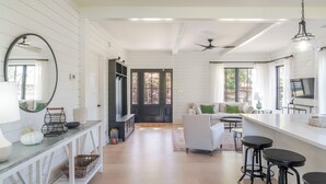 A spacious kitchen with a bar area, white cabinetry, and a large window. - Fox Cottage – Modern Wine Country Retreat in Afton, VA (Afton)