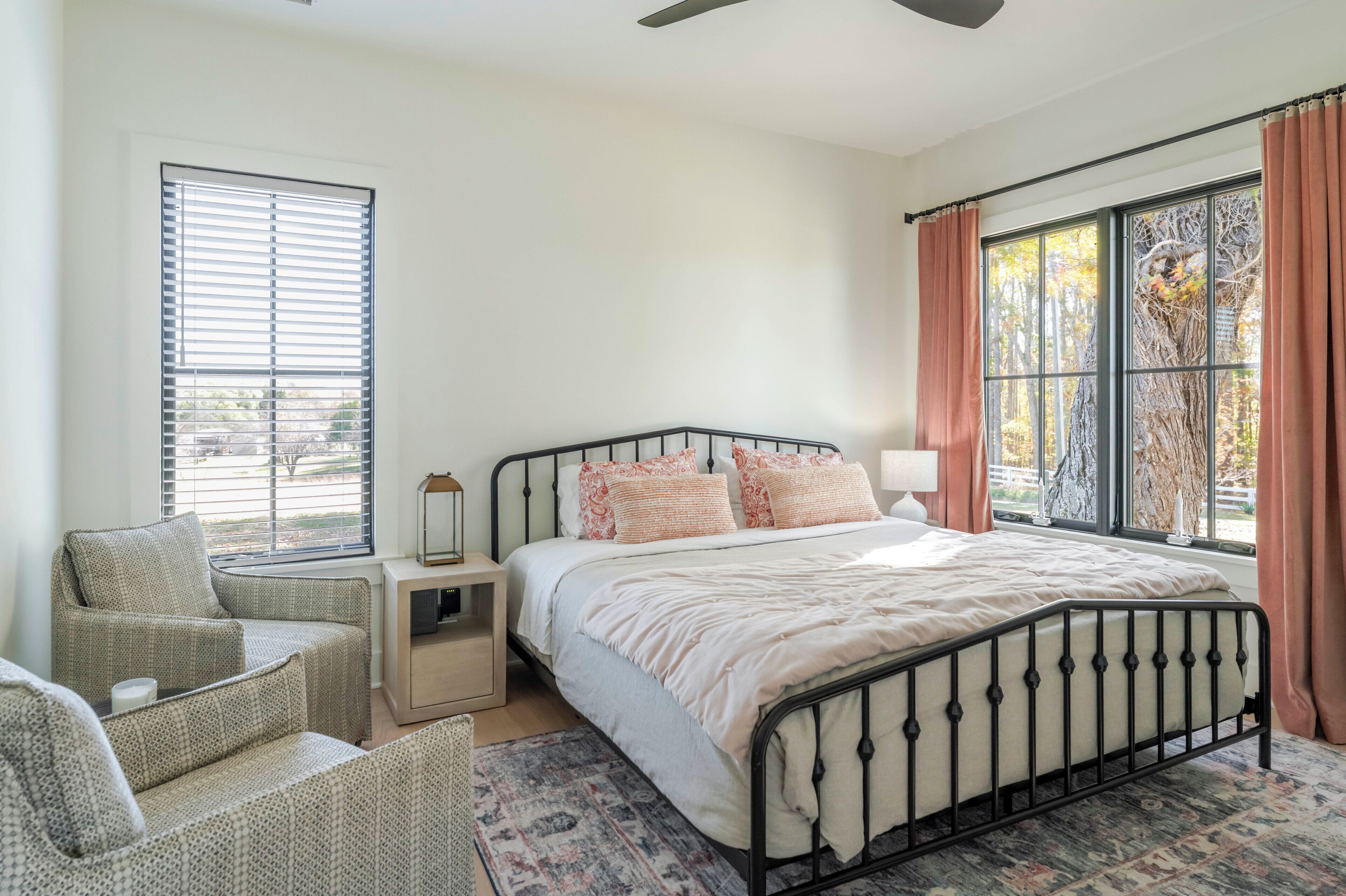 A bedroom with a bed, a nightstand, a chair, and a window with curtains.