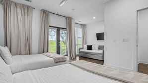 Ein Schlafzimmer mit Bett, einer Couch, einem Deckenventilator und Blick ins Freie.