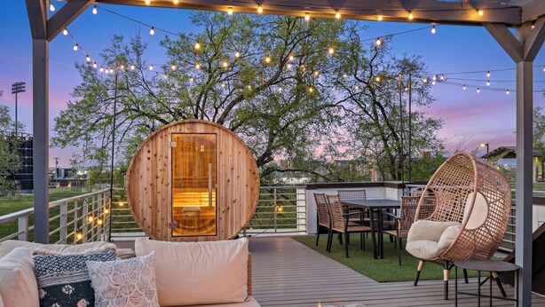 Eine Holzterrasse mit Feuerstelle, Sitzgelegenheiten und Lichterketten.