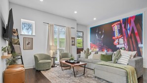 Ein Wohnzimmer mit Sofa, Sessel, Couchtisch und einem großen Wandbild.