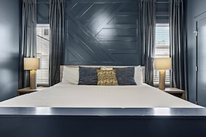 A bed with a headboard, two bedside tables, and a lamp on each side.