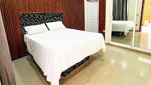 A bedroom with a bed, wooden paneling, a ceiling fan, and a sliding glass door. - Villas cloud 1 (Santo Domingo)