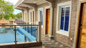 A hotel with a pool, a balcony with a glass railing, and a brick exterior. - Villas cloud 1 (Santo Domingo)
