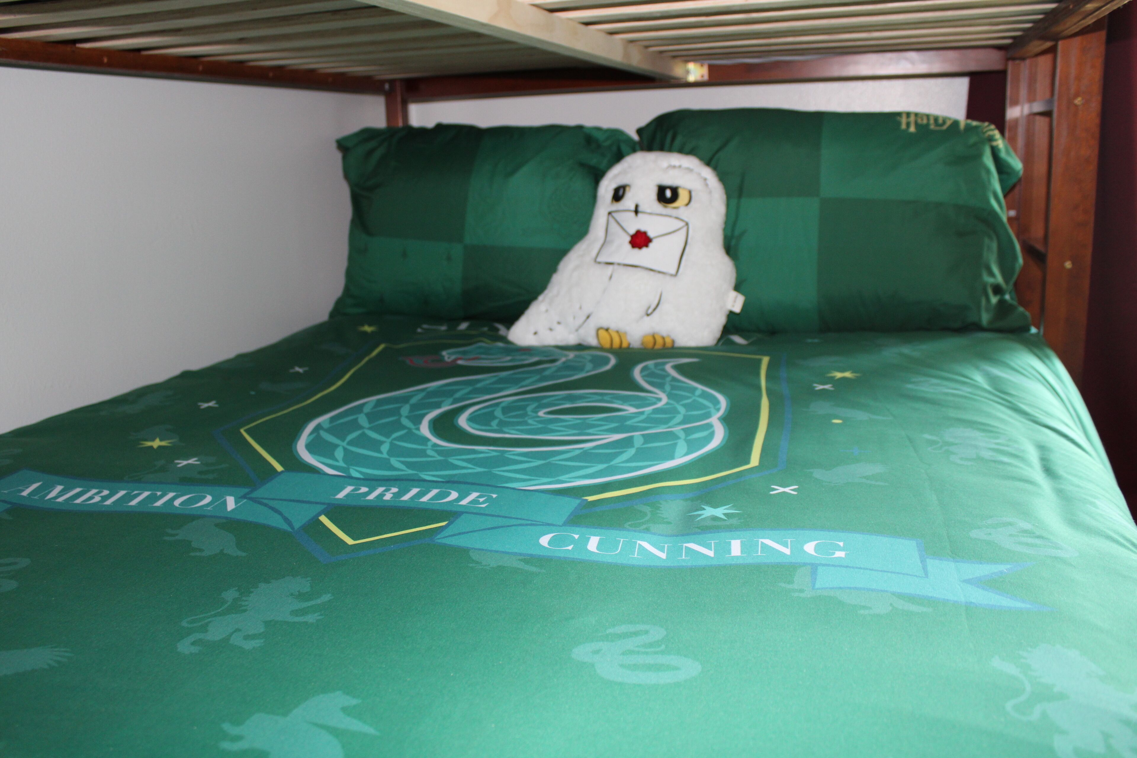 Ein Bett mit einer grünen Decke, die ein Logo und das Wort "CUNNING" zeigt.
