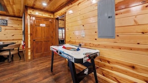 A wooden interior with a table for foosball, a door, and a wall-mounted light switch.
