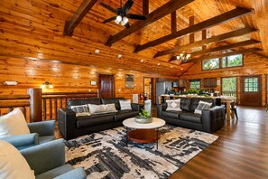 A spacious living area with a large black sectional sofa, a coffee table, and a patterned rug. - 8-Bedroom Cabin with Indoor Pool, Mini Golf & Hot Tub, Sleeps 30 (Sevierville)
