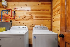 Une buanderie équipée de deux lave-linge Whirlpool, avec des murs en bois et des tuyaux apparents.