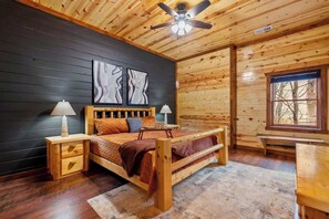 A wooden cabin bedroom with a bed, nightstands, and a window. - 8-Bedroom Cabin with Indoor Pool, Mini Golf & Hot Tub, Sleeps 30 (Sevierville)