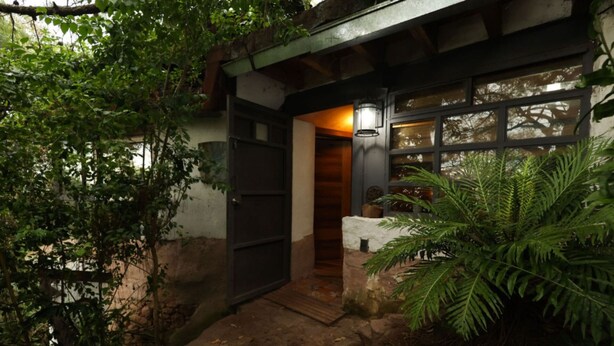 A rustic building with a wooden door and a small porch area. - Bio-built Retreat in the Nature of Valle de Bravo (Valle de Bravo)