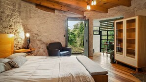 A bedroom with a large bed, a chair, and a wardrobe. - Bio-built Retreat in the Nature of Valle de Bravo (Valle de Bravo)