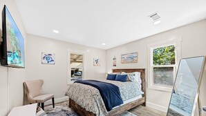 Une chambre à coucher avec un lit, une chaise, un bureau et des œuvres d’art accrochées aux murs.