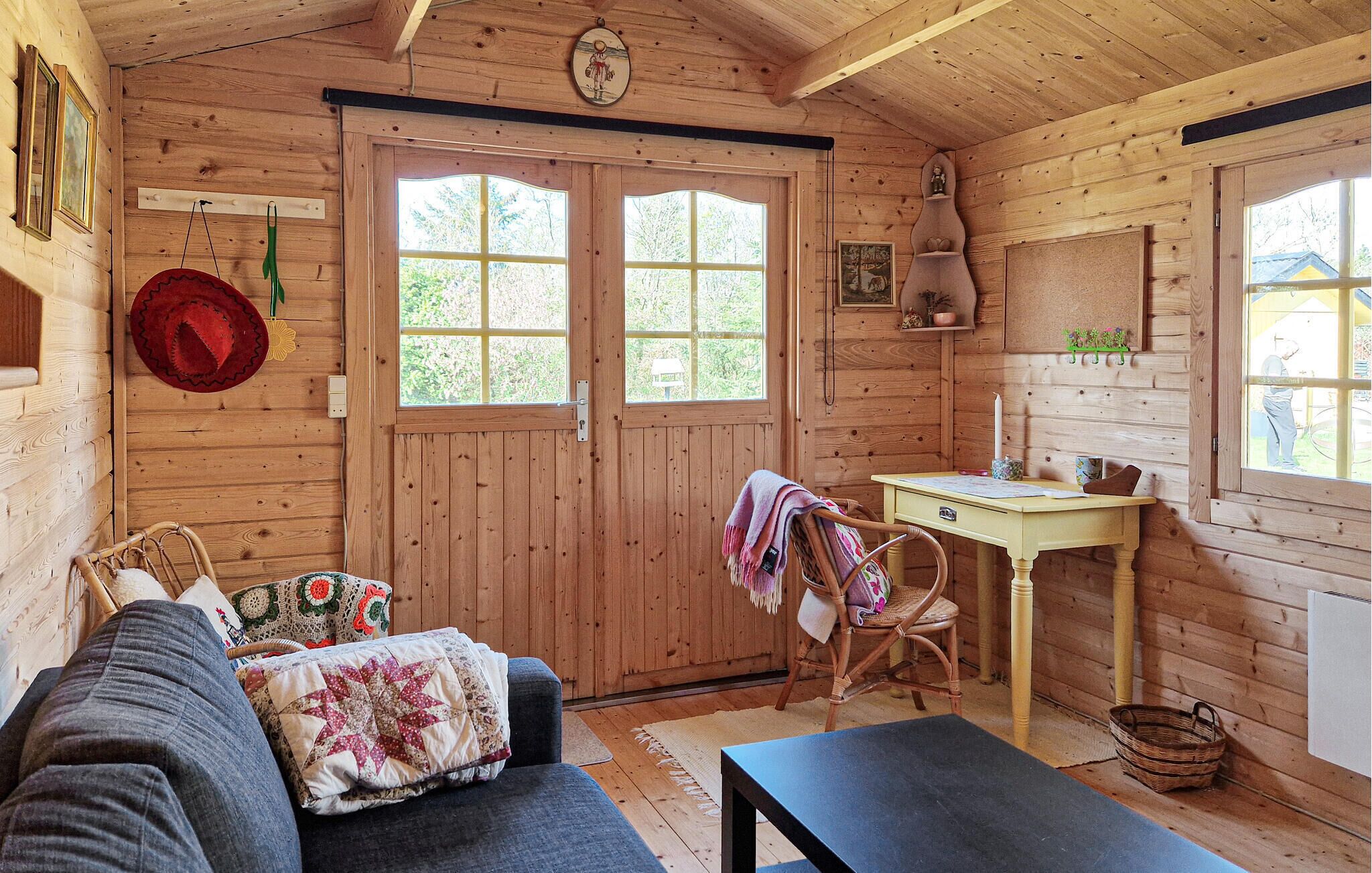 A cozy cabin interior with a wooden door, a small table, a chair, and a sofa.