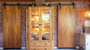 A wooden cabinet with glass doors against a brick wall, containing dishes and glassware. - 2 bedroom awesome home in Tarm (Tarm)