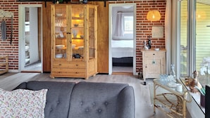 A cozy room with a wooden cabinet, a grey sofa, and a small table with decorative items. - 2 bedroom awesome home in Tarm (Tarm)