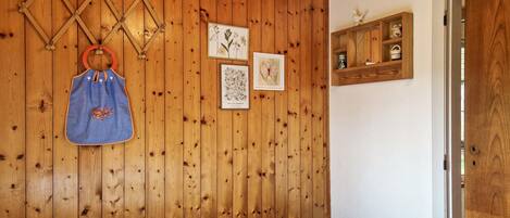 Een kamer met houten lambrisering, een bed, een wandrek en een plank met decoratieve objecten.